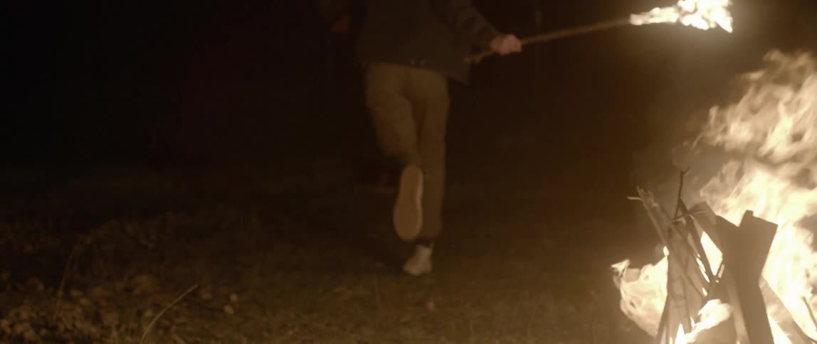 A man runs with a burning torch and starts a bonfire