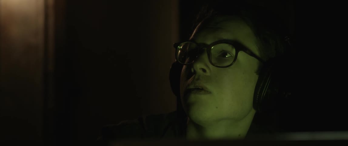 A man wearing headphones looks up from his monitor