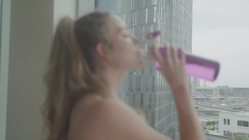 A woman is drinking from a water bottle