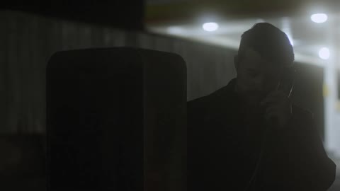 A man talks on a payphone at night