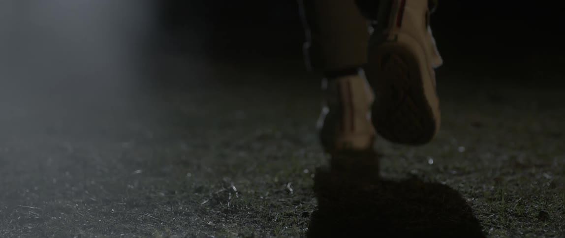 A person walks on the grass at night