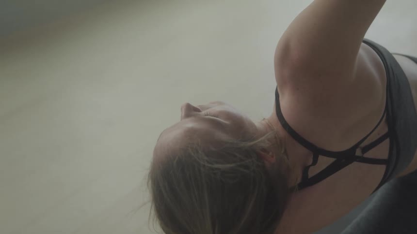 A woman stretches in a yoga pose on a wooden floor