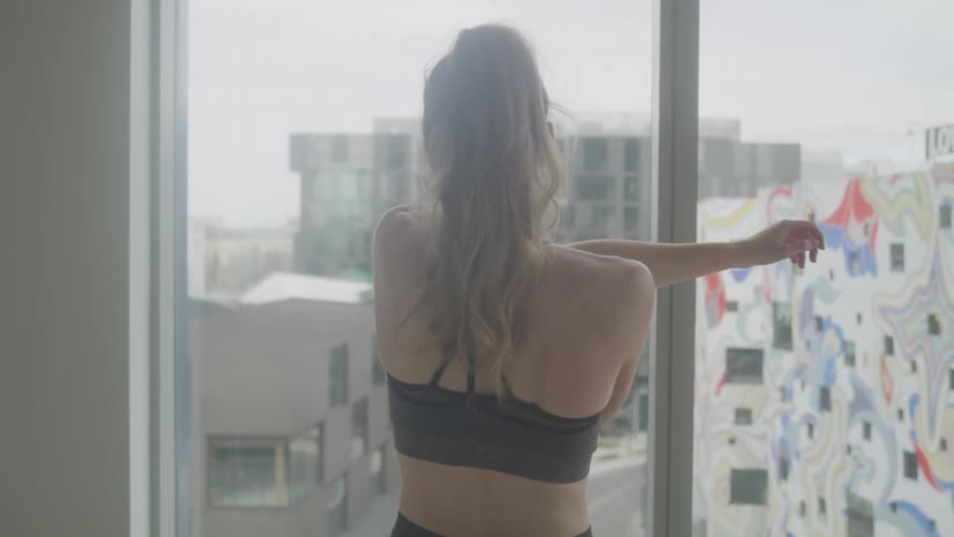 A woman is stretching by the window