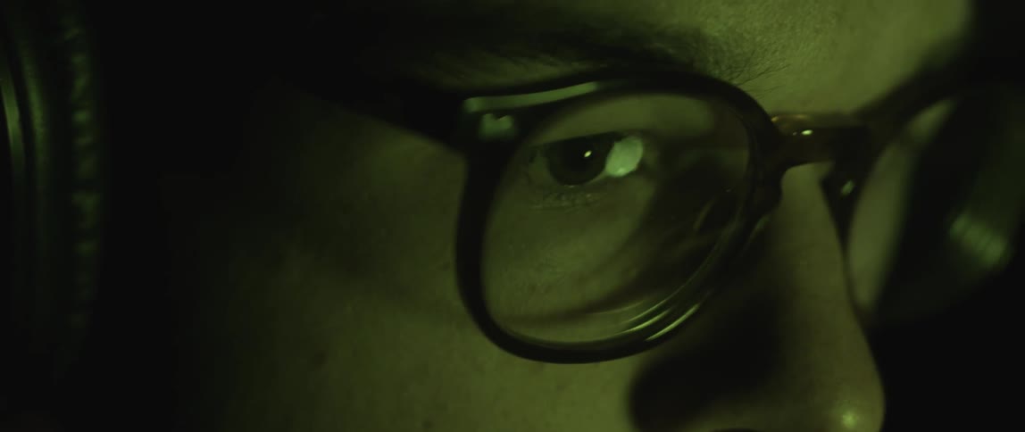Light reflects on a man's eyeglasses