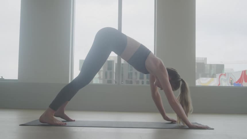 A woman is doing yoga and on leaning forward