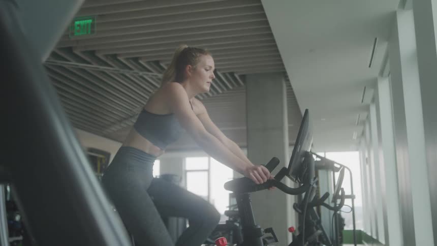 A woman is pedaling in the gym