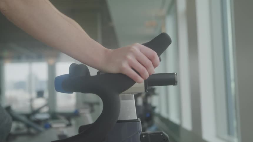 Female gripping handlebars of stationary bike during a workout