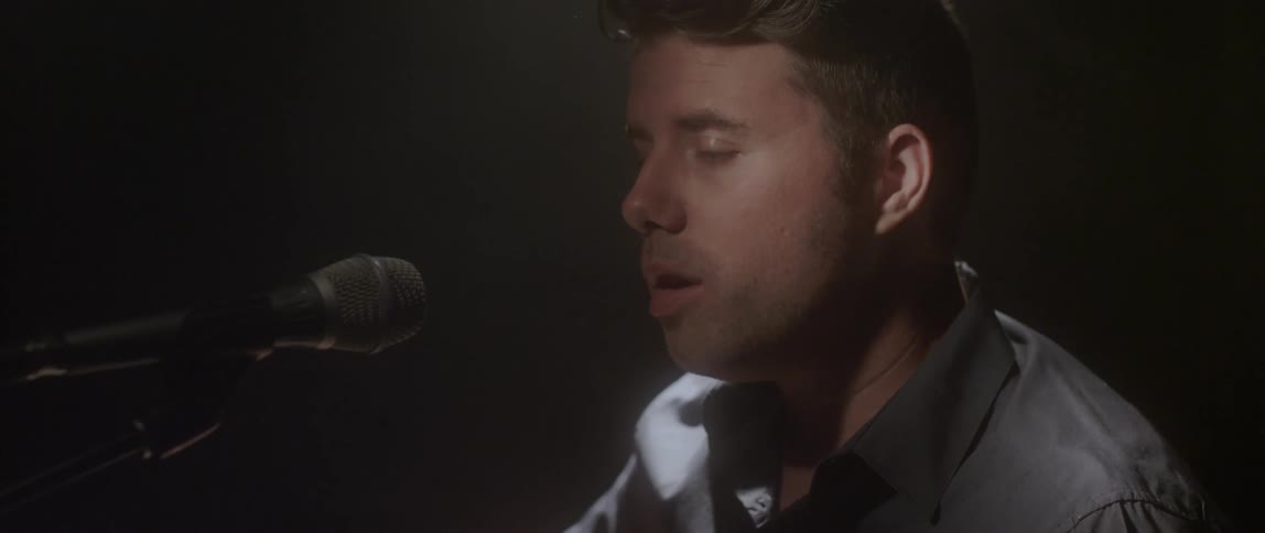 Man singing passionately into a microphone that's in front of him