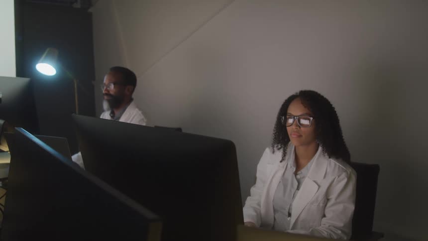 A man and woman are typing at their computers in the office
