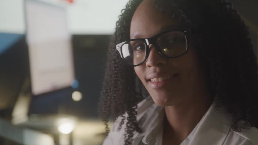 Woman working at a computer table in the office turns her head with a smile