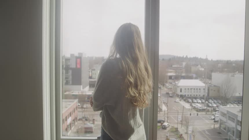 A footage of a lady standing beside the window
