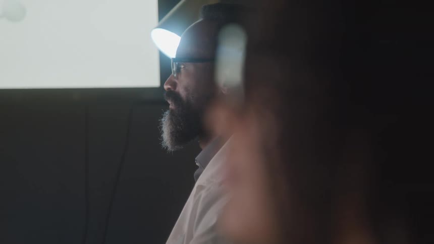 Two people sit together studying something with a screen next to them displaying a mind map