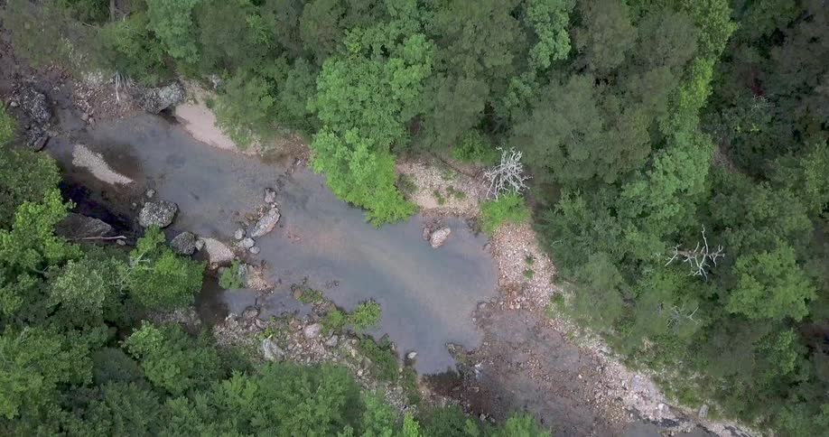 An overhead view of a creek with a lot of trees