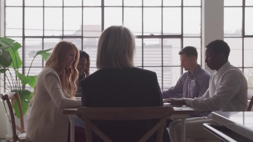Coworkers smile during a meeting near large windows on a foggy day