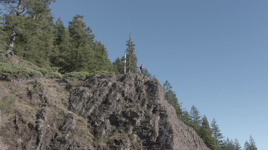 A hiker walks to the cliff on the tall mountain