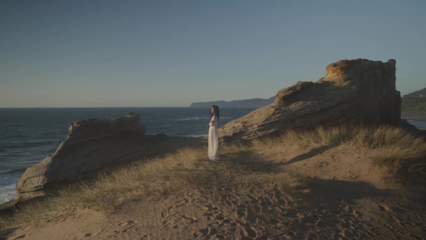 Girl in white dress in a rock above the coast
