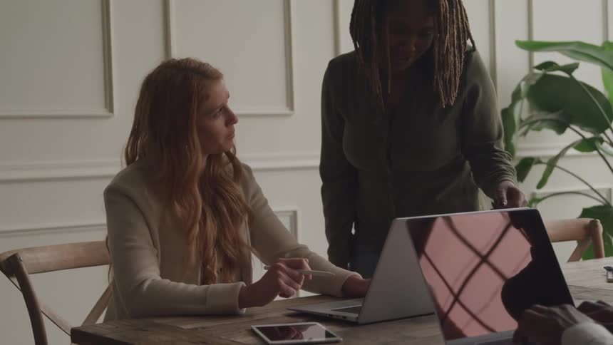 Women talk and look at a laptop in the office