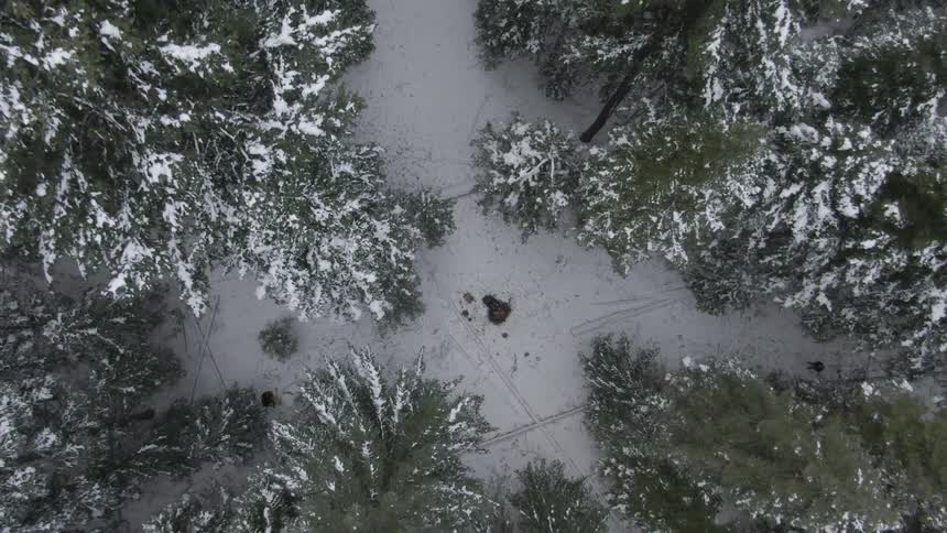 A man is sitting close to the campfire in the snow