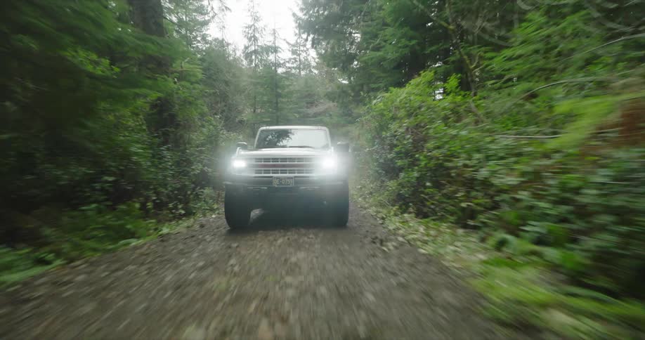 A truck drives into camera on the dirt road in the forest
