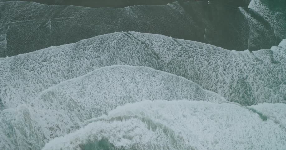 Birds eye view of waves rapidly rolling onto the shoreline