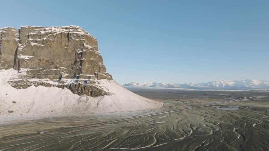 A vehicle drives past the mountain on the large landscape
