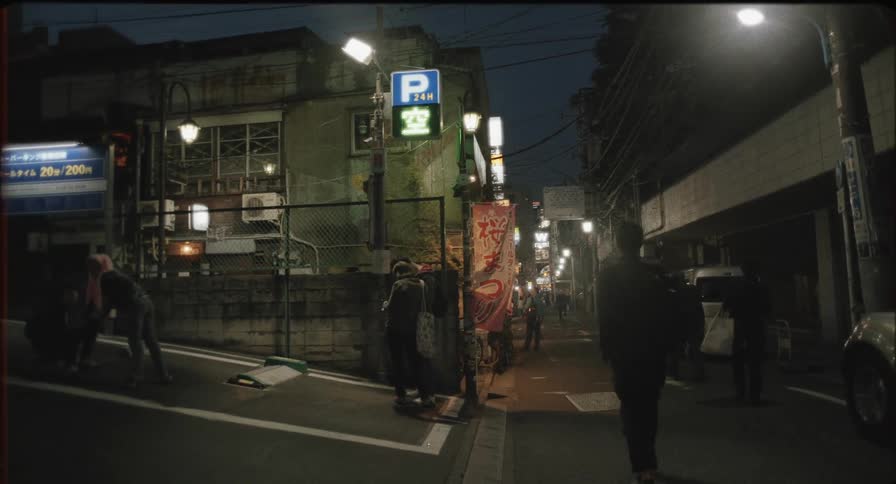 People walk down the small road in the city at night