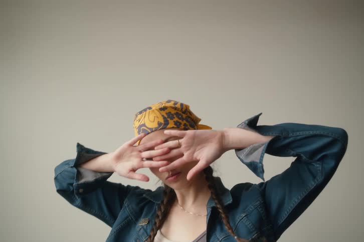 A woman poses and puts her hands in front of her face