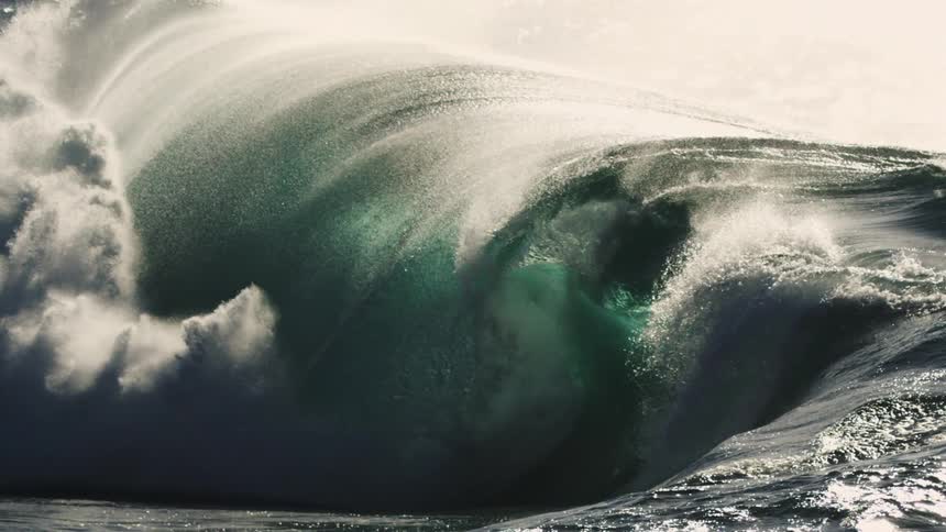 A large powerful wave curls and crashes in the ocean its dark green water contrasting with the white spray and foam creating a dynamic and dramatic scene