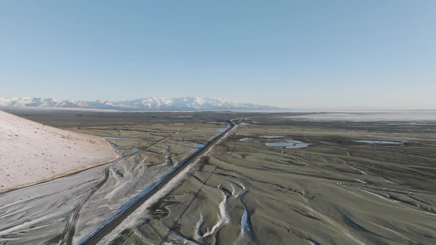 A car drives down a road in a wide open space