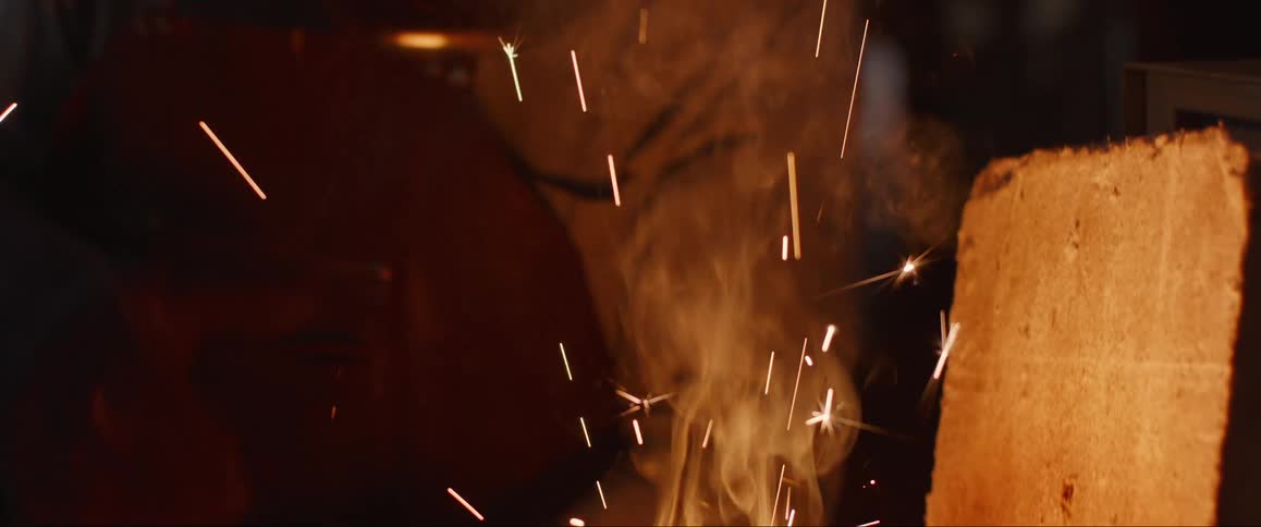 Molten material glows intensely within a crucible emitting smoke and sparks in a hightemperature environment