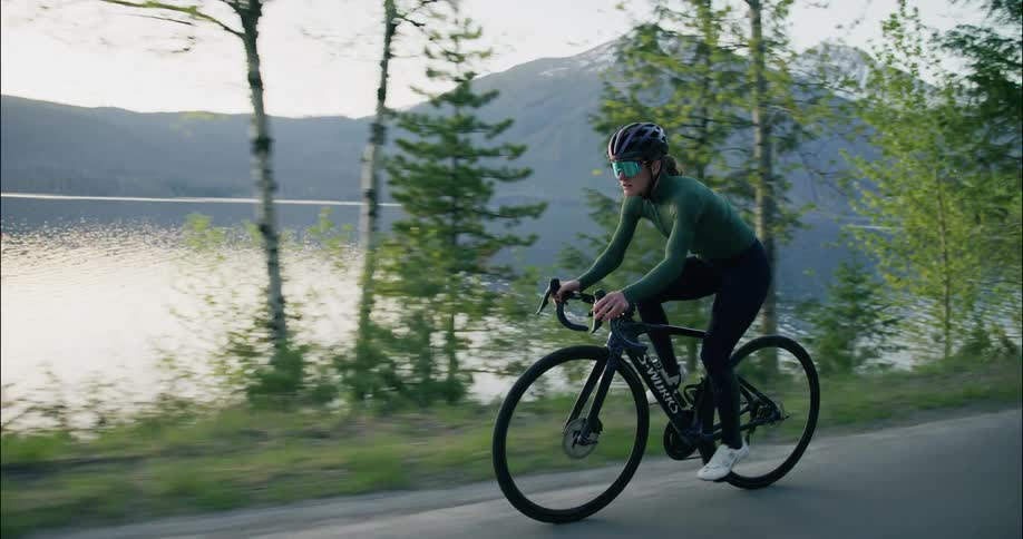 Cyclist riding on road alongside the lake in the mountains