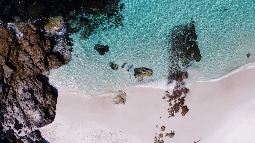 An aerial footage of people walking into the sea