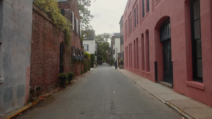 An empty narrow street lined with buildings of varying colors and architectural styles under a muted sky