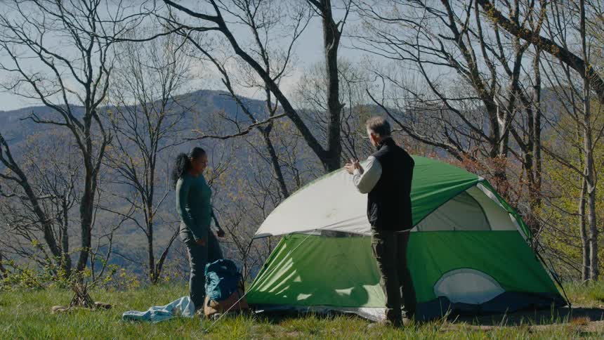 A man and woman finish building a tent together
