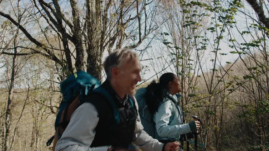 Pair of friends laughing and chatting while hiking through the wilderness