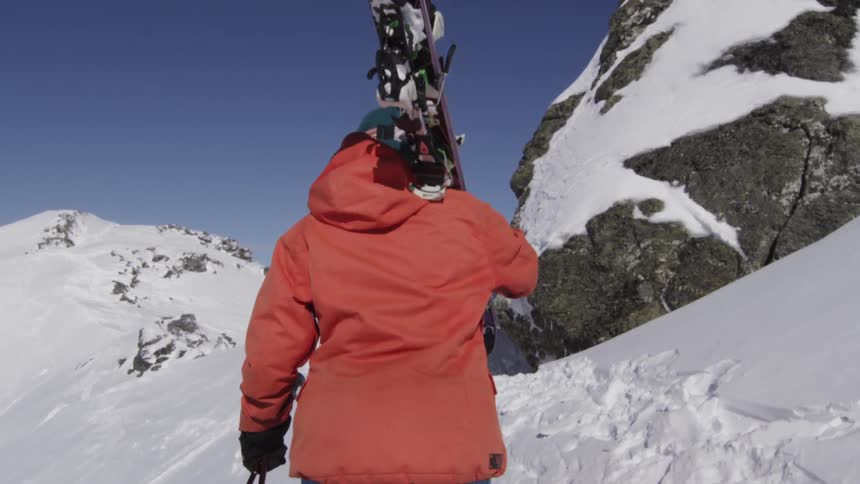 A person carries their skis up a snowy mountain