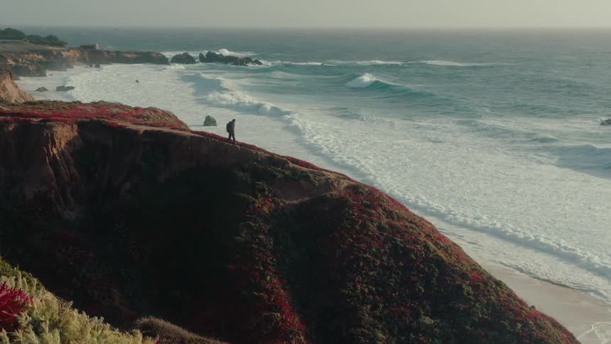 A man hikes on a hill on the beach