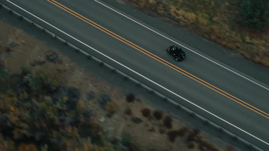 A motorcycle carrying two people drive down the road
