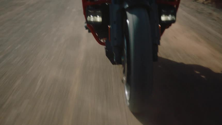 A person rides a motorcycle down the street in a rural area