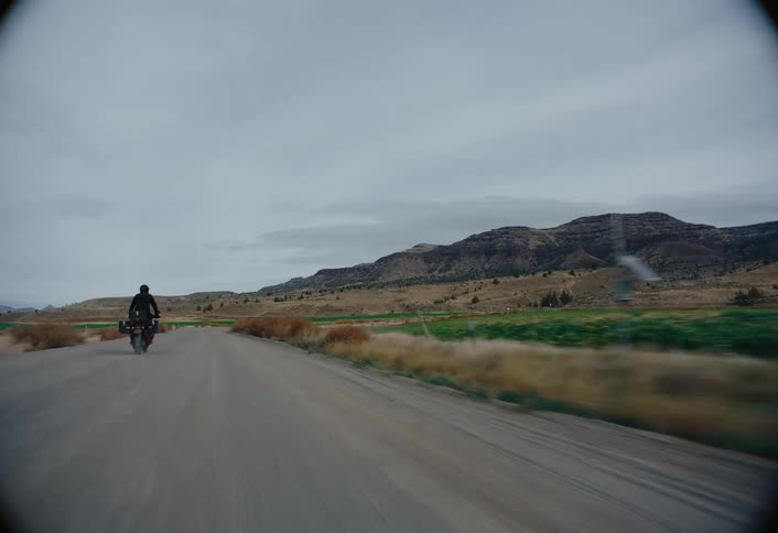 A person riding a motorcycle on an asphalt road in a rural area