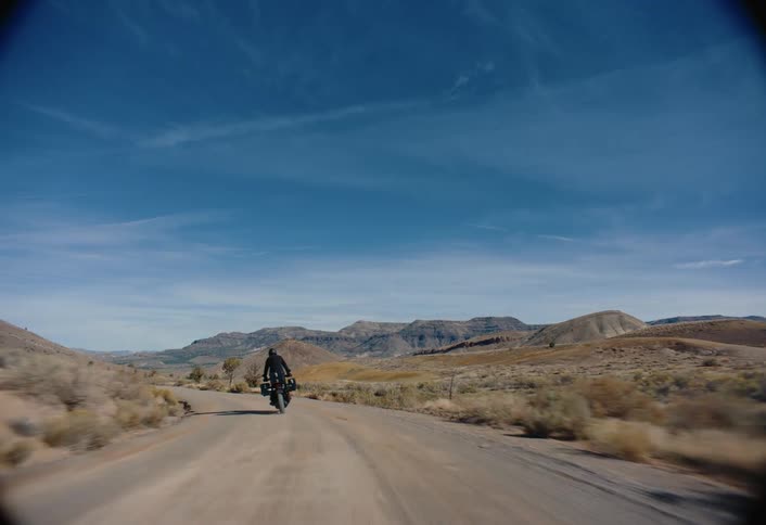 A motorcycle riding through the desert towards mountains