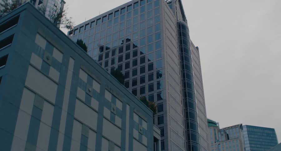 Tall buildings reflect the cloudy sky