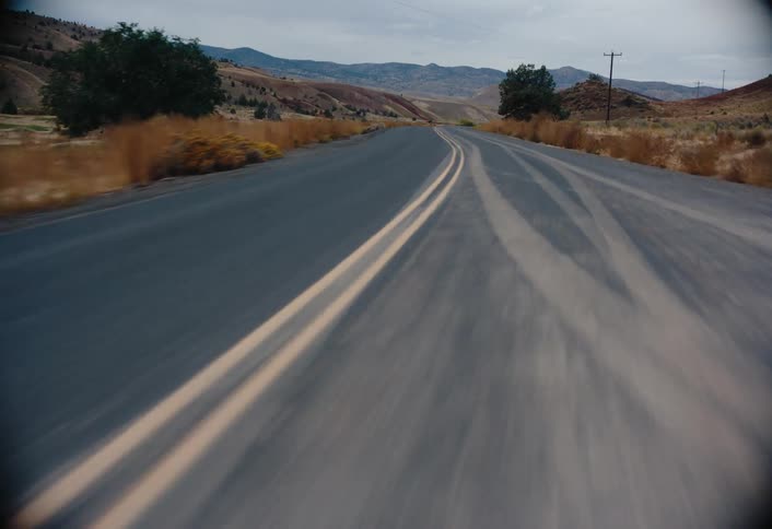 A winding road runs through a scenic countryside with hills and trees