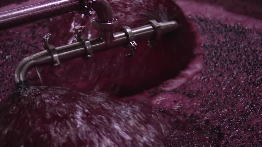 A sprayer spraying a vat full of blueberries with blueberry juice