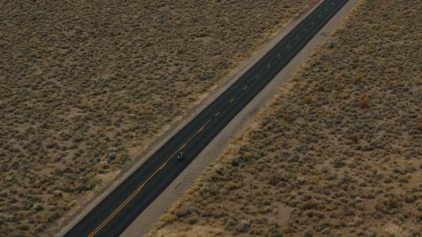 The motorcycle drives alone on the road in the desert