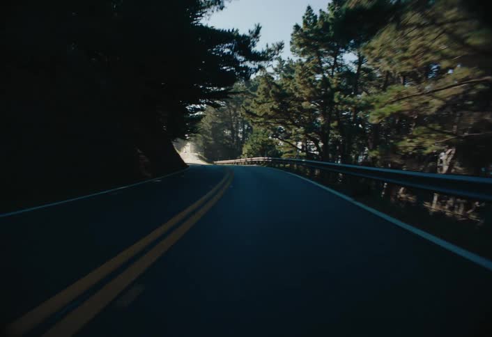 A footage of a car motion on the freeway in the middle of the forest