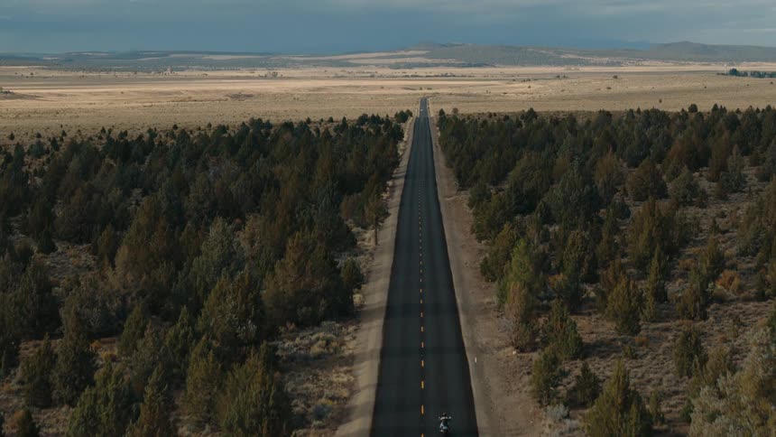 A motorcycle is traveling down the long road on the landscape