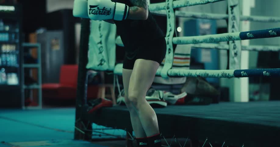 A woman gets up and walks away from the boxing ring