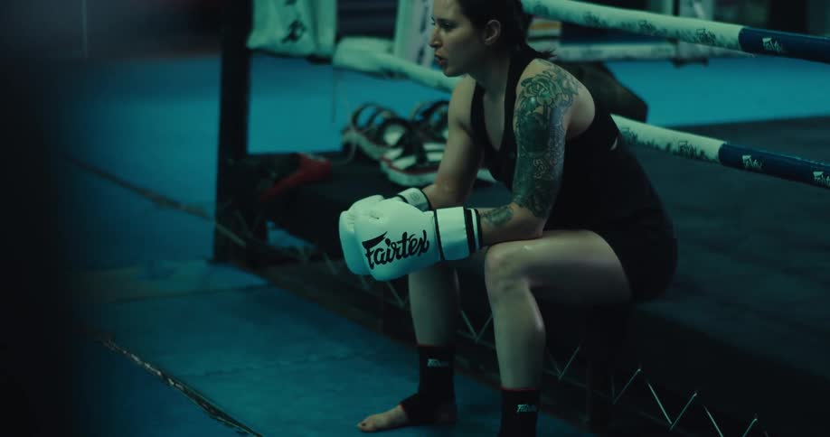 A woman gets up from sitting on the boxing ring