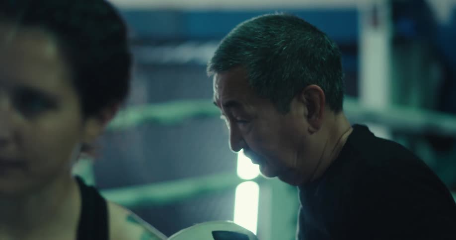 A woman is training at boxing with a man